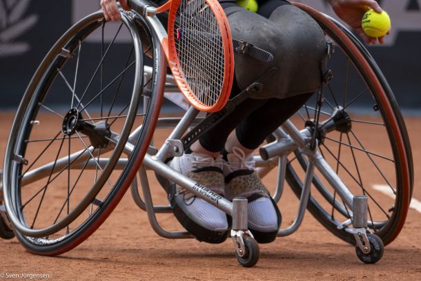 Beine eines Tennisspielers im Rollstuhl auf dem Tennisplatz