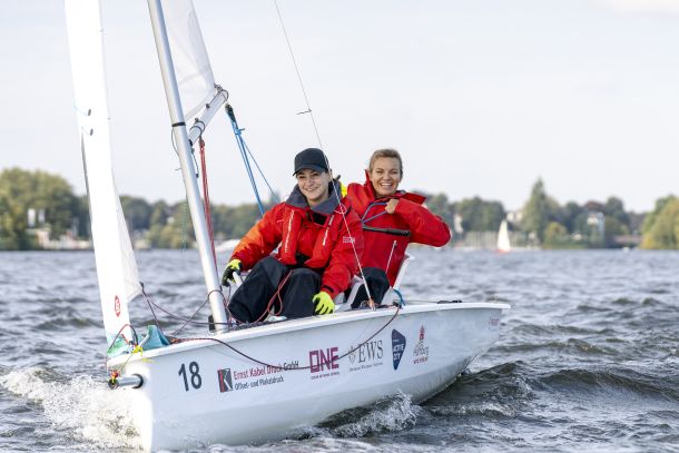 zwei seglerinnen mit roten Jacken auf dem inklusiven Boot SV/14, die in die Kamera lächeln