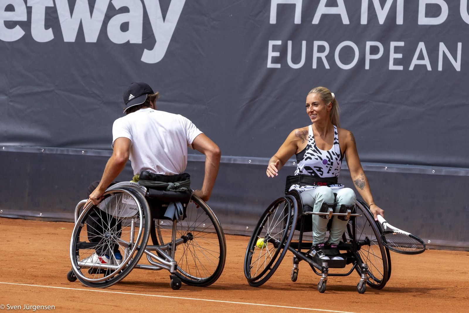 Ein Tennisspieler und eine Tennisspielerin im Rollstuhl die sich anschauen